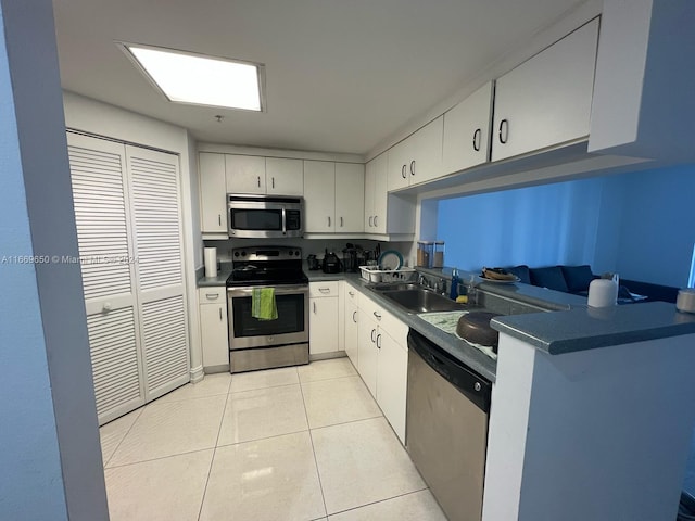 kitchen with light tile patterned floors, stainless steel appliances, sink, and white cabinets