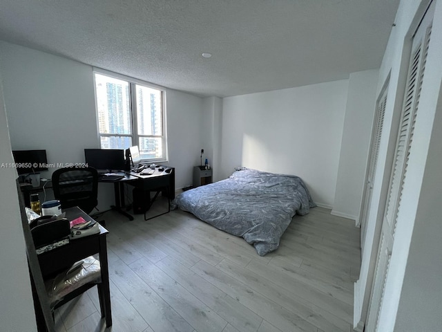 bedroom with a textured ceiling and light hardwood / wood-style flooring