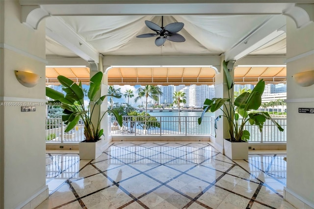 unfurnished sunroom with a water view and ceiling fan