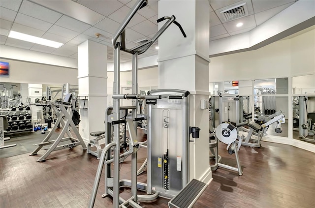 workout area featuring a drop ceiling, a towering ceiling, and hardwood / wood-style floors