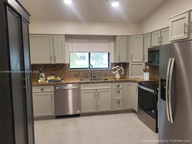 kitchen featuring decorative backsplash, gray cabinetry, stainless steel appliances, and a sink