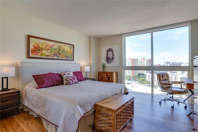 bedroom with expansive windows, hardwood / wood-style floors, and a textured ceiling