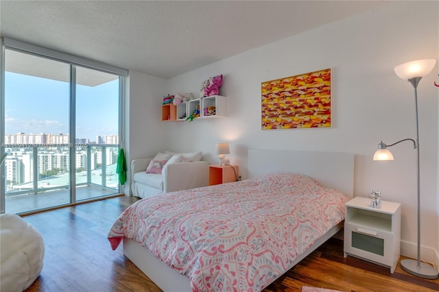 bedroom featuring dark hardwood / wood-style flooring, access to outside, floor to ceiling windows, and a textured ceiling