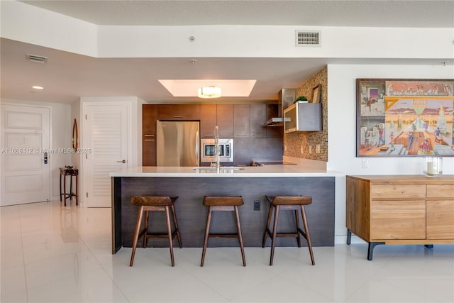 kitchen featuring sink, a breakfast bar area, appliances with stainless steel finishes, kitchen peninsula, and backsplash