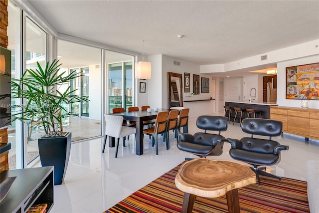 dining room featuring floor to ceiling windows, sink, and a textured ceiling