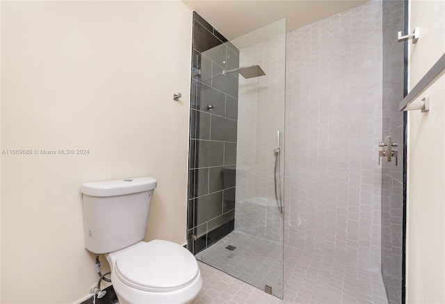 bathroom featuring a tile shower, tile patterned flooring, and toilet