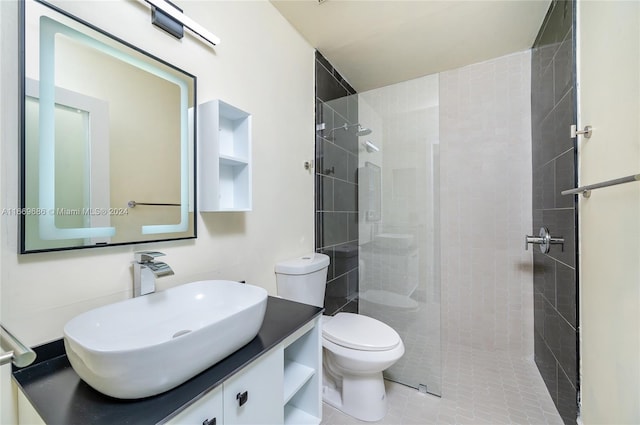 bathroom featuring tile patterned flooring, tiled shower, vanity, and toilet