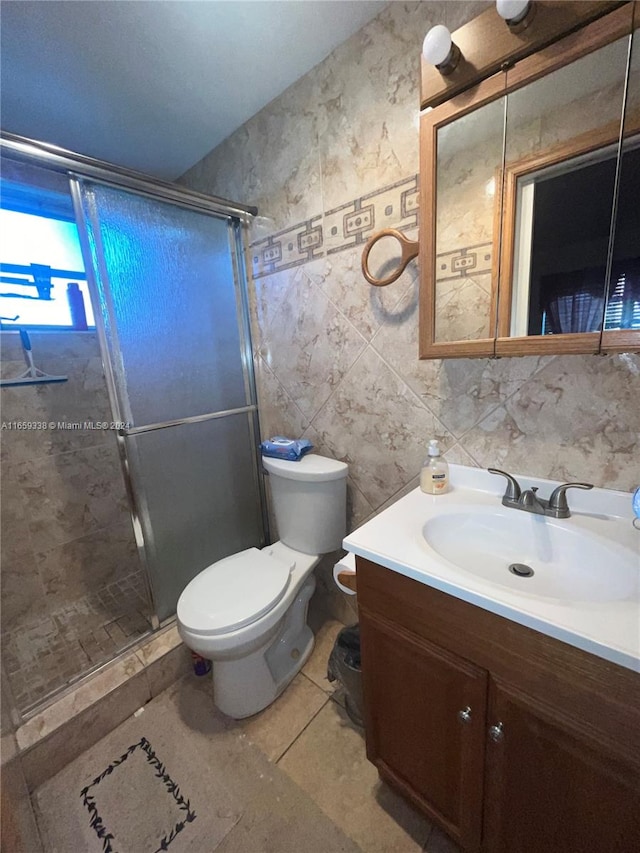 bathroom featuring a shower with door, toilet, tile walls, vanity, and tile patterned flooring