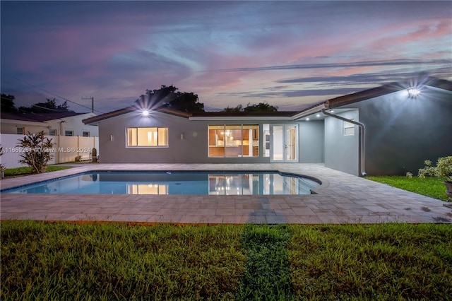 pool at dusk featuring a patio