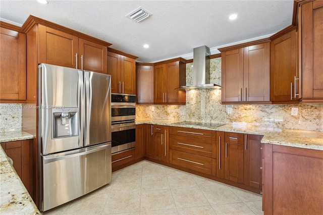 kitchen with appliances with stainless steel finishes, a textured ceiling, wall chimney range hood, and light stone counters