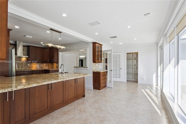 kitchen featuring a textured ceiling, wall chimney exhaust hood, backsplash, and ornamental molding