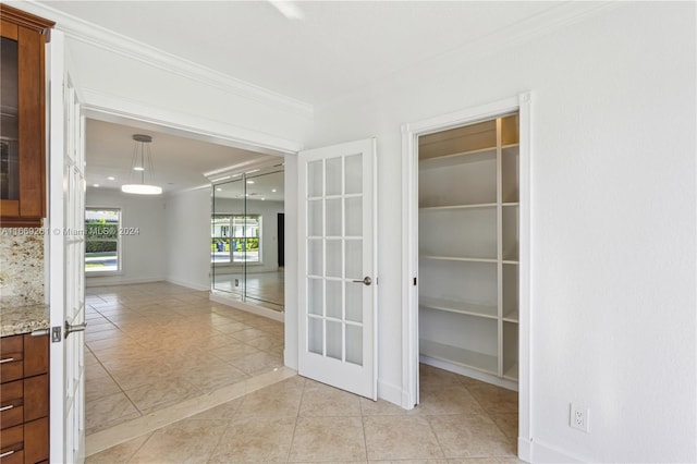 interior space with french doors, light tile patterned floors, and ornamental molding