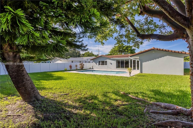 rear view of property featuring a yard and a fenced in pool