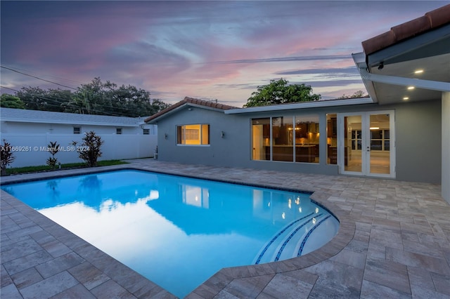 pool at dusk featuring a patio