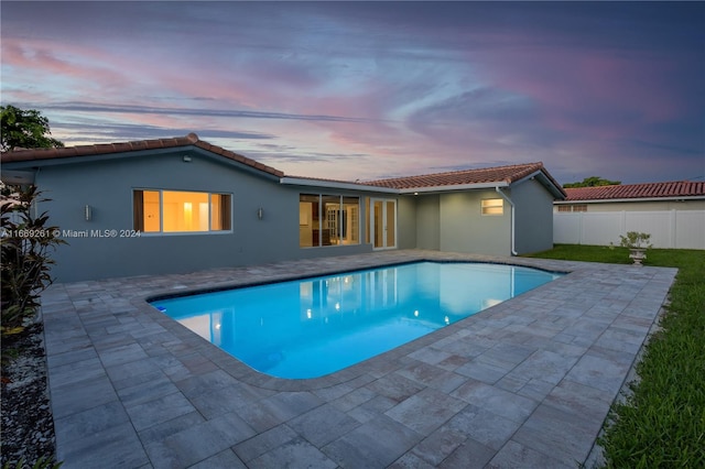 pool at dusk with a patio area