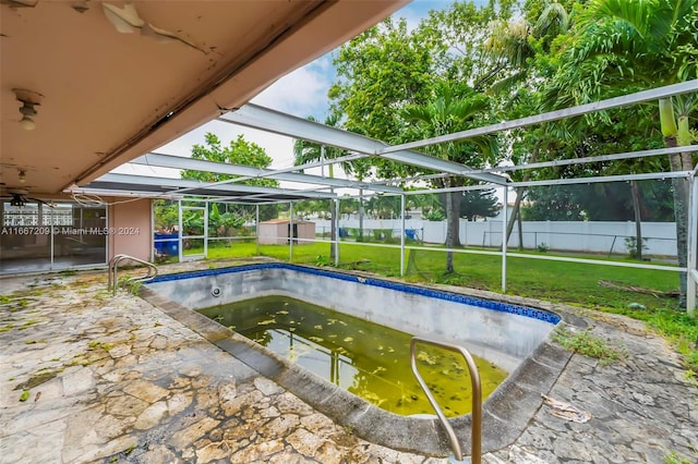 view of pool with a lawn and a lanai