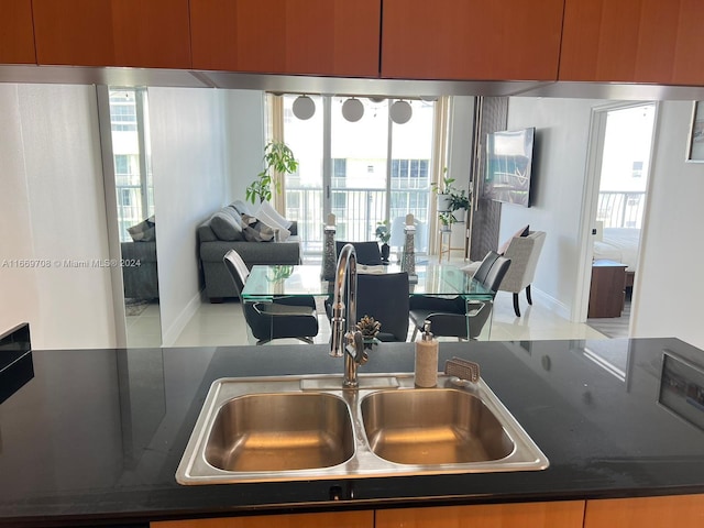 kitchen with dark stone countertops, light tile patterned floors, and sink