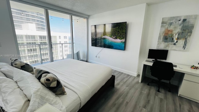 bedroom with access to outside, hardwood / wood-style flooring, built in desk, and a textured ceiling