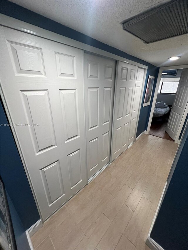 hallway featuring light hardwood / wood-style floors and a textured ceiling