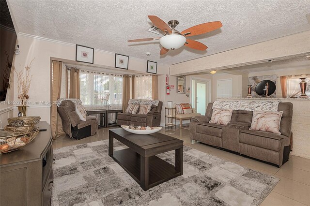 living room with a textured ceiling, light tile patterned flooring, ceiling fan, and crown molding