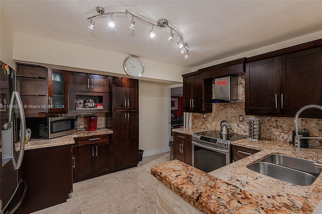 kitchen featuring dark brown cabinetry, light stone countertops, appliances with stainless steel finishes, and sink