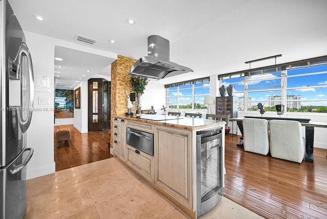 kitchen with stainless steel refrigerator, island range hood, light brown cabinets, light wood-type flooring, and beverage cooler