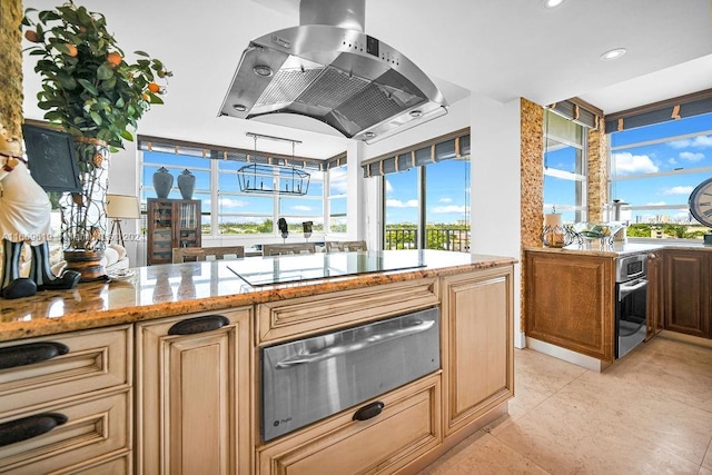 kitchen featuring light tile patterned flooring, island range hood, oven, light stone countertops, and gas stovetop