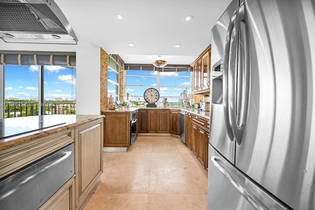 kitchen featuring stovetop, wall chimney range hood, stainless steel fridge with ice dispenser, and a healthy amount of sunlight