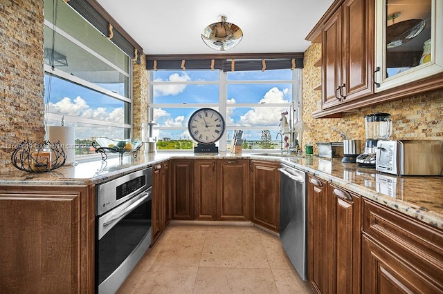 kitchen featuring decorative backsplash, sink, stainless steel appliances, and light stone counters