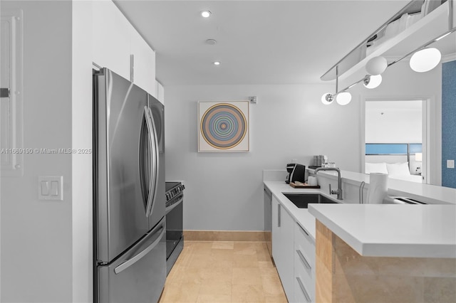 kitchen with kitchen peninsula, stainless steel appliances, sink, light tile patterned floors, and white cabinets