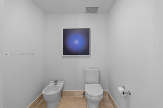 bathroom featuring toilet, tile patterned floors, and a bidet