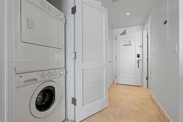 laundry area featuring light tile patterned floors and stacked washing maching and dryer