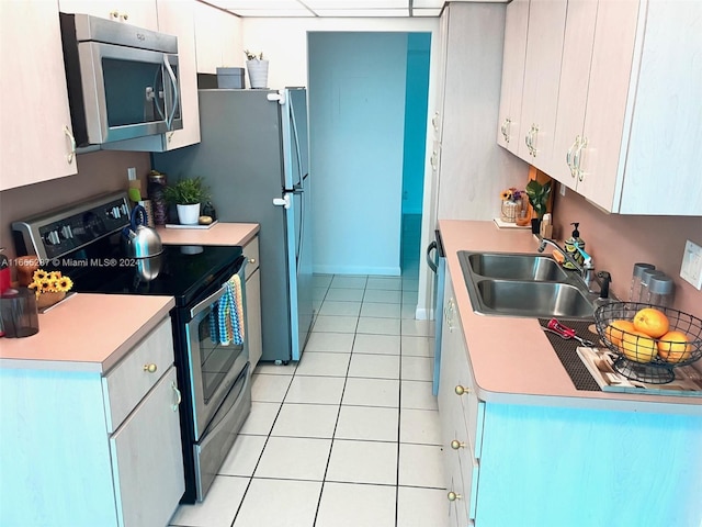 kitchen with white cabinetry, appliances with stainless steel finishes, light tile patterned flooring, and sink