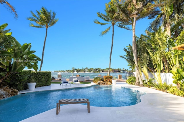 view of swimming pool with a patio area, a water view, and pool water feature