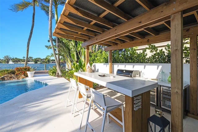 view of patio / terrace with wine cooler, grilling area, a fenced in pool, exterior bar, and an outdoor kitchen