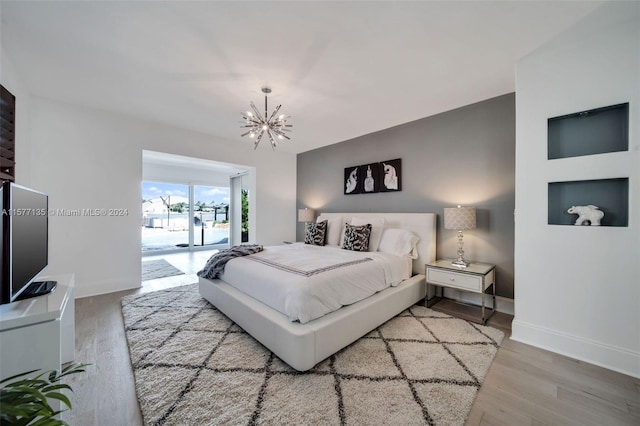 bedroom featuring an inviting chandelier, hardwood / wood-style floors, and access to exterior