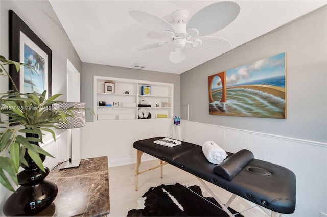 living room with built in shelves, light hardwood / wood-style flooring, and ceiling fan