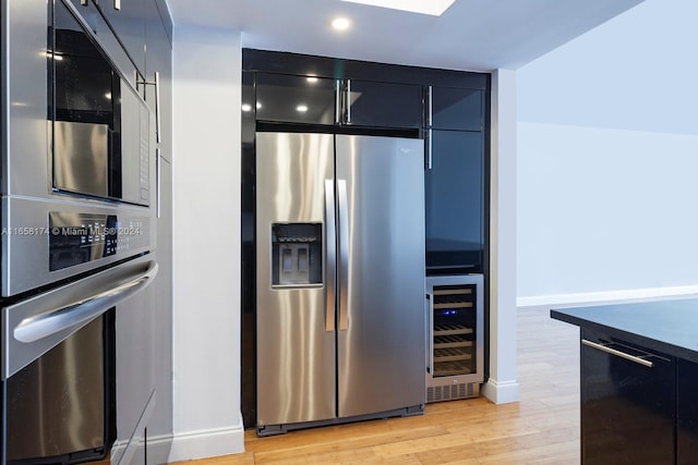 kitchen with beverage cooler, light hardwood / wood-style flooring, and stainless steel appliances