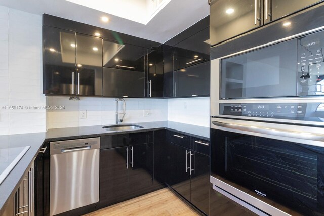 kitchen featuring sink, appliances with stainless steel finishes, light hardwood / wood-style floors, and decorative backsplash