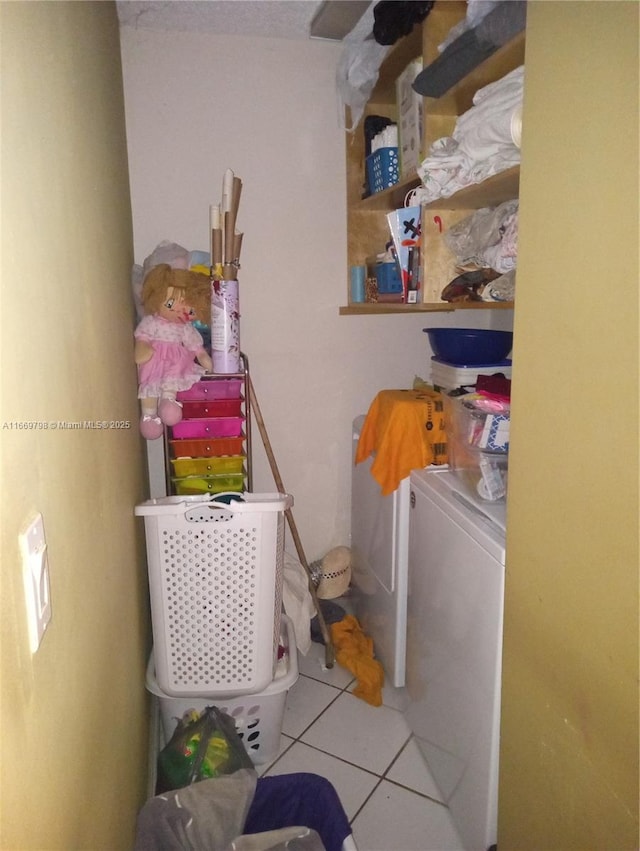 clothes washing area featuring light tile patterned floors and washing machine and clothes dryer