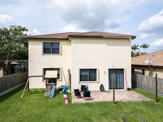 back of property featuring a patio area, a lawn, and a playground