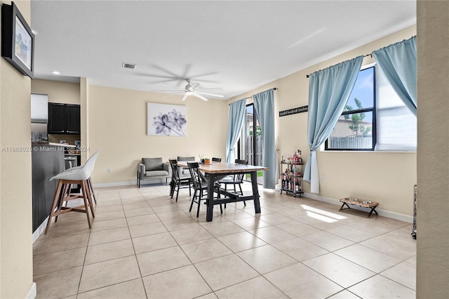 dining space featuring a textured ceiling, ceiling fan, and light tile patterned flooring