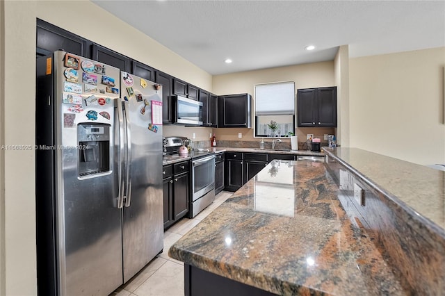 kitchen featuring appliances with stainless steel finishes, dark stone counters, sink, and light tile patterned flooring