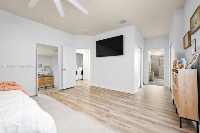 bedroom featuring light wood-type flooring, ensuite bath, ceiling fan, and washing machine and clothes dryer