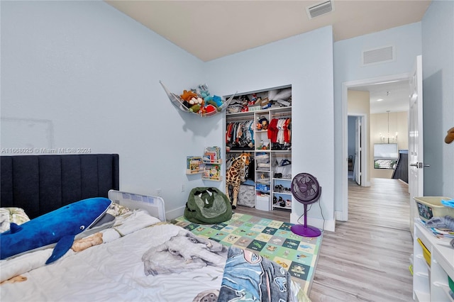 bedroom with a closet, an inviting chandelier, and light hardwood / wood-style floors