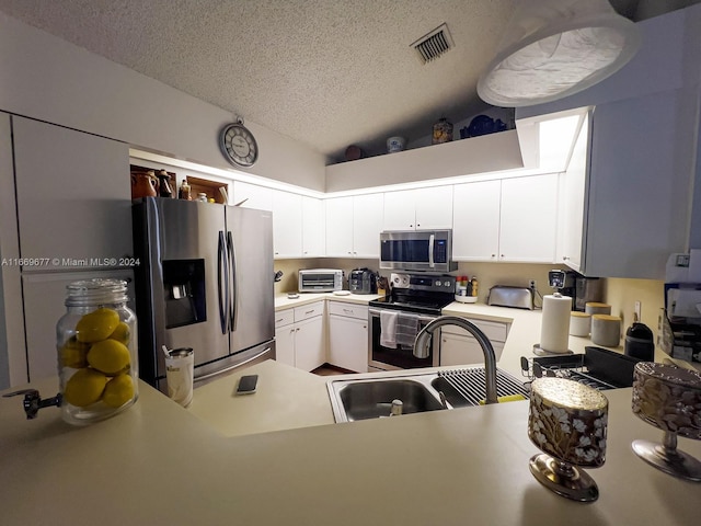 kitchen featuring sink, a textured ceiling, white cabinetry, appliances with stainless steel finishes, and vaulted ceiling