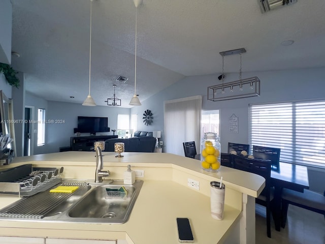 kitchen featuring a textured ceiling, vaulted ceiling, and sink