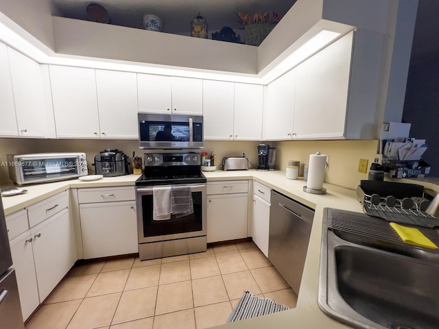 kitchen featuring white cabinets, appliances with stainless steel finishes, light tile patterned flooring, and sink