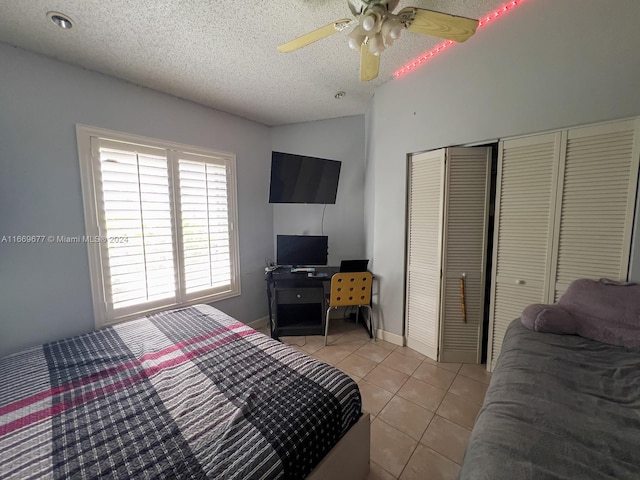 bedroom with a textured ceiling, light tile patterned flooring, and ceiling fan