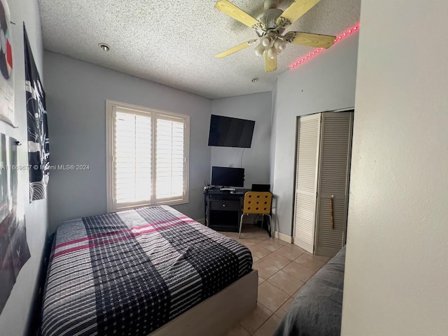 bedroom with ceiling fan, a textured ceiling, a closet, and light tile patterned flooring